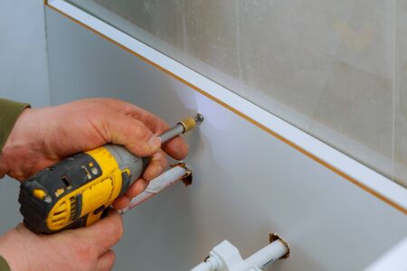 A new bathroom furniture carpenter installing a new bathroom wood cabinetの写真素材