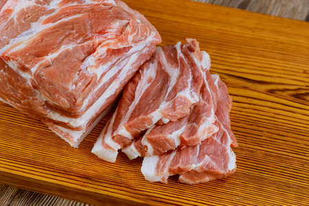 Pieces of raw fresh pork steak with on a wooden boardの写真素材