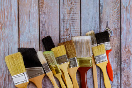 Painter work table repair, renovation painting different size paint brushes on wood background