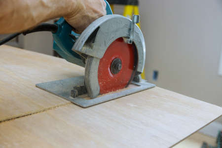 Works sawing plywood with electric circular saw at cutting wooden plywood