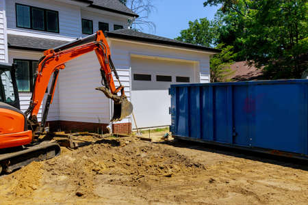 Mini excavator and bobcat on construction site for working in trash container construction dumpsters
