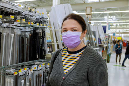 A young woman face under the a medical mask buying in a supermarket with coronavirus COVID-19