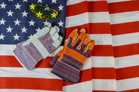 Happy federal holiday Labor day construction leather gloves tools on over American flag background.
