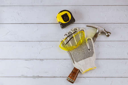 Contractor woodworking with safety work gloves hammer and tape measure safety glasses on wooden boardの写真素材