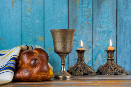 Shabbat candles in glass candlesticks of covered challah bread soft focus