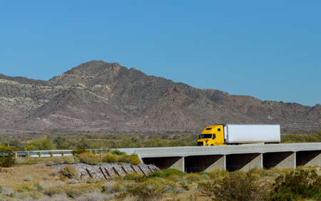 Big rig long haul semi truck with two flat bed semi trailers transporting on the winding road with...