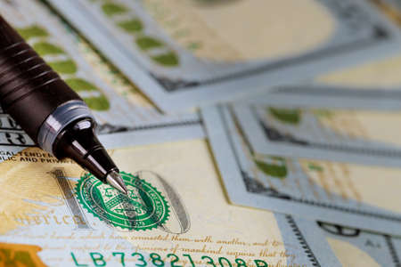 One hundred dollars pile as with ballpoint pen on dollars banknotes background