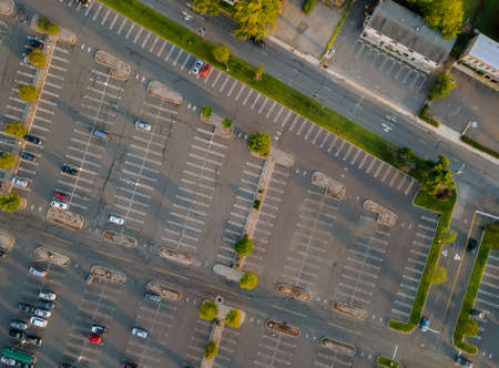 Aerial view of a large number of cars of different brands standing in a parking lot near the shopping center in a parking divided by white dividing strips and sidewalksの写真素材