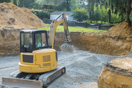Excavator digging bucket scooping gravel from in the building foundation