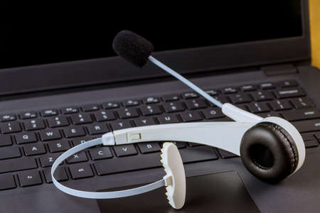 VOIP headset headphones with microphone communication support, call center and customer service help desk on computer keyboard.の写真素材