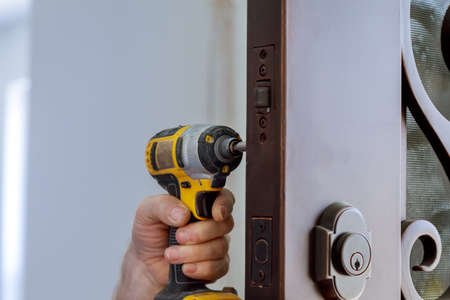 Locksmith in installing new house door lock hand holds the screwdriverの写真素材