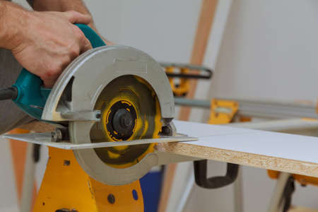 Master cutting hand electric saw cut a piece of wood laminated shelves in apartmentの写真素材