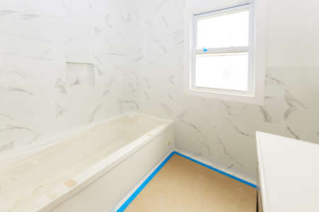 Bathroom with tiled walls and floor installing shower and sink, is in the apartment that is under construction of homeの写真素材