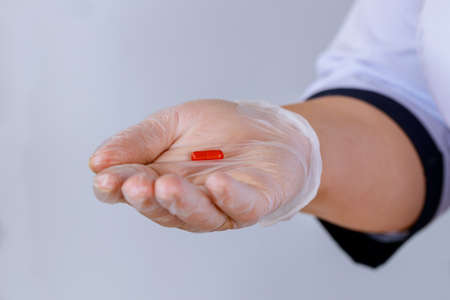 Doctor holding in pill in a hand on isolated white backgroundの写真素材
