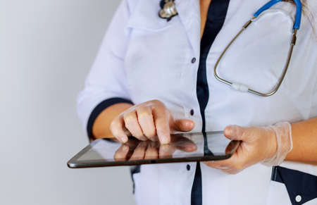 Female physician using digital tablet while standing near desk at clinic emergency hospital doctor at work.の写真素材