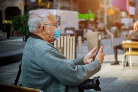 People wearing protective face masks outdoors due to coronavirus epidemic on man with his smartphone in New York USAの写真素材