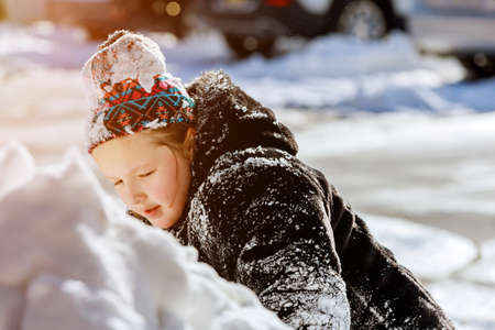 Snow on home drive way little caucasian child play outdoors on snowyの写真素材
