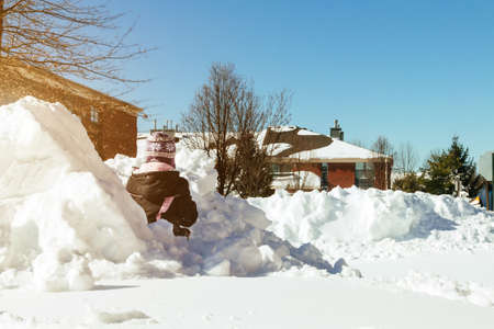 Girl child playing with snow in winter in the sunny day