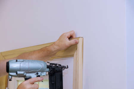 Carpenter installing nailing the framing trim to moldings on doors