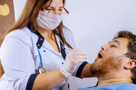 A man in a clinical setting being swabbed by a healthcare worker in determine if he has contracted the coronavirus COVID-19.の写真素材