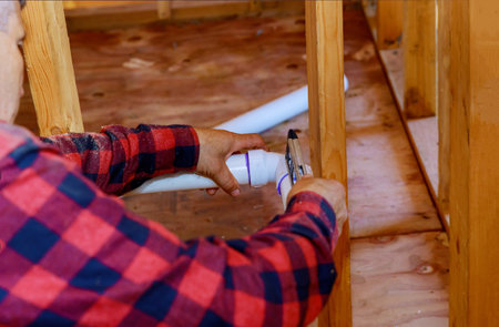 Hands plumber in installing of plastic drains PVC pipe, close up on new bathroomの写真素材