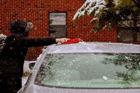 Winter snowstorm woman remove after snow from windshield with car cleaning snowの写真素材