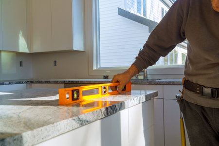 Under construction with worker checks the leveling of a granite slab for use in a home kitchen...