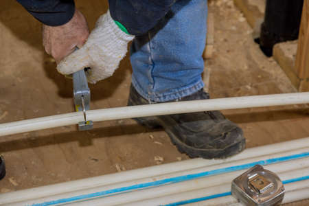 Maintenance plumber man hand using pvc pipe cutter for cut the water pipe a water supply system on...