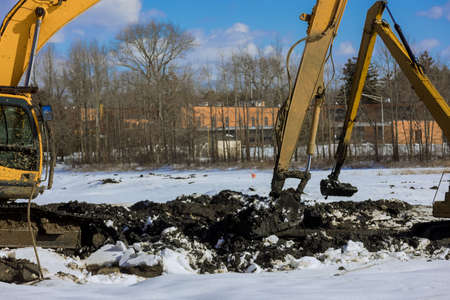 Excavator working on earthmoving at pit on winter backhoe digs, in the heavy construction equipment...