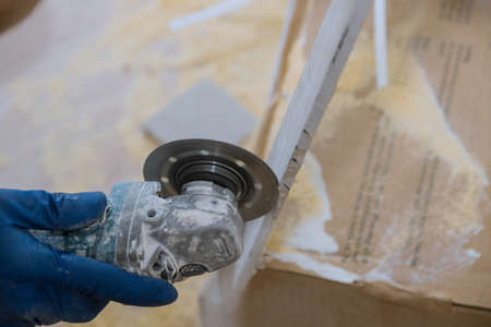 Construction trimming tiles worker cutting a tile using grinder