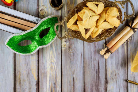 Top view from above on Jewish carnival Purim celebration on hamantaschen cookies, noisemaker and mask with parchmentの写真素材