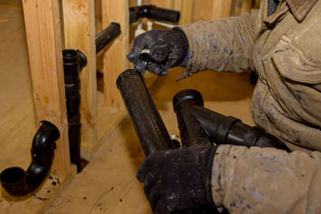 Plumbing building contractor installing plastic drain pipe in the elbow for sink drain for a custom...