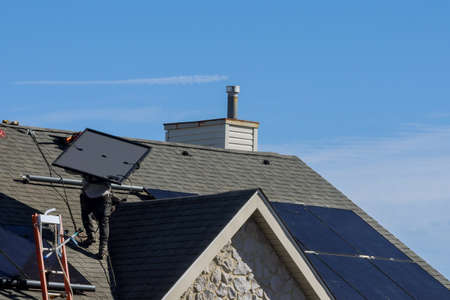 Work man installing photovoltaic solar panels alternative energy on roof