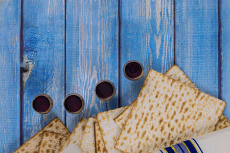 Wine with kosher four glasses of matzah a Passover Haggadah on a vintage wood background