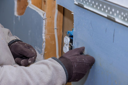 Replacement of the old outlet with a new one in closeup of hand of electricianの写真素材