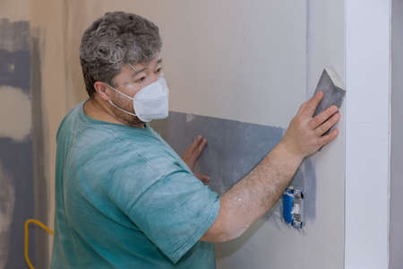 Contractor using sand trowel sanding the plaster plasterboard