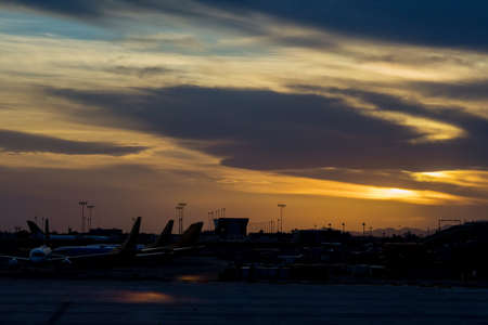 During sunset with airport many aircraft lined up on the terminal gateの写真素材