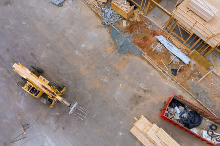 Aerial view of forklift stacker wooden boards and trash dumpsters construction on apartment framing...