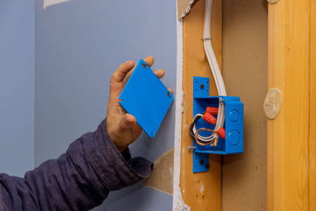 Hands of an electrician fasten the electrical box to the beams to placeの写真素材