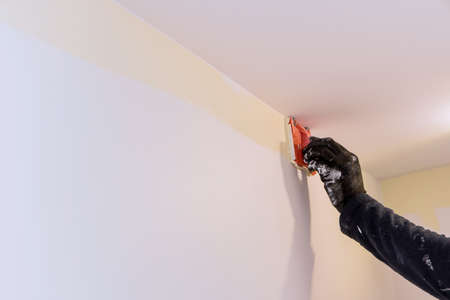 Working contractor painter hands with painting the wall on corner paint edger home renovationの写真素材