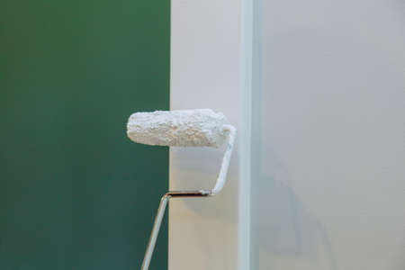 Contractor painter updating colors of painting doors molding trim using hand roller painting with...