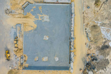 Aerial view on the construction site of mounting concrete brick walls on foundation pit