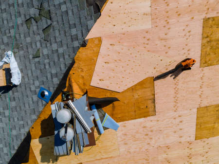 A worker replace shingles on the roof of a home repairing the roof of a homeの写真素材