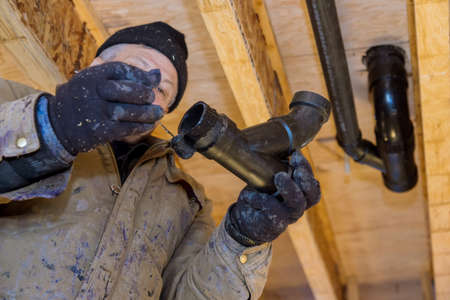 Plumber hands in glue pieces of plastic drains PVC pipe, close up on new bathroom