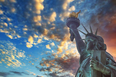 Dramatic view of the Statue of Liberty, with Manhattan in a red sunset background in America