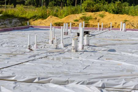 PVC drain pipes in a new house in foundation slab preparation for concrete pour at construction site.の写真素材