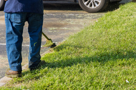 Professional municipal worker using mower mowing the grass in roadside
