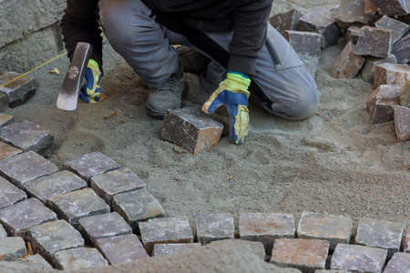 Construction worker installing stone on road is putting down pavers during a reconstruction road