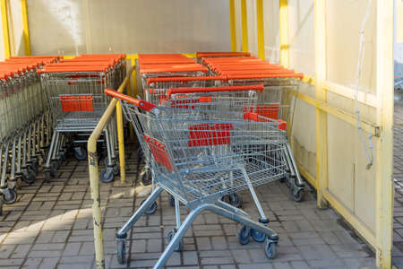 A row of metal shopping carts near a shopping center are placed in a row in a hypermarket the store