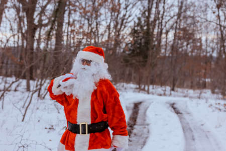 Santa Claus in the winter forest the carrying Merry Christmas present gifts for the new year to childrenの写真素材